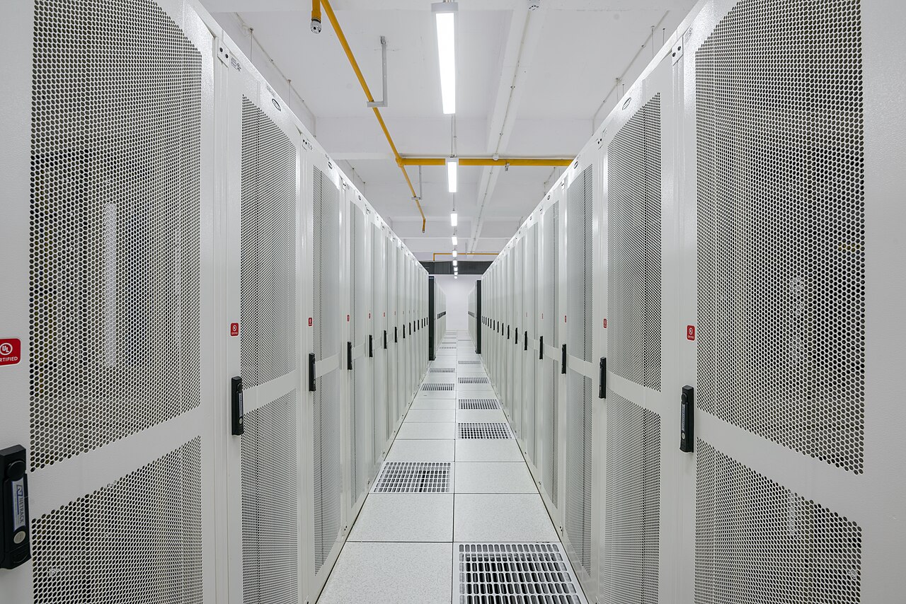 A long, brightly lit corridor between rows of white server racks