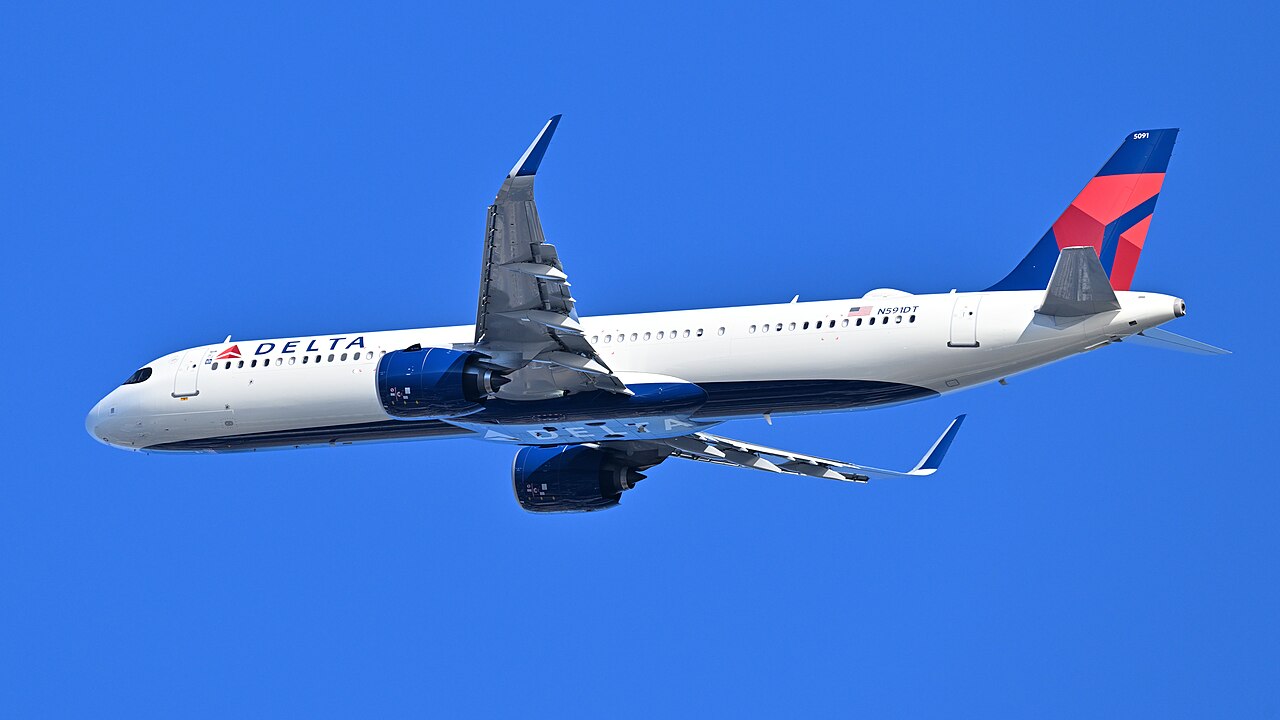 A white Delta Air Lines jet with a red and blue tail climbing just after takeoff