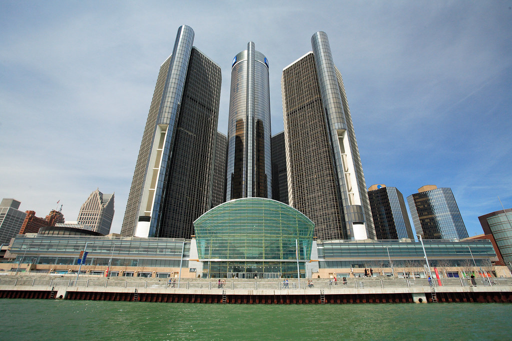 Glass towers of a riverfront office complex seen from the water under a blue sky